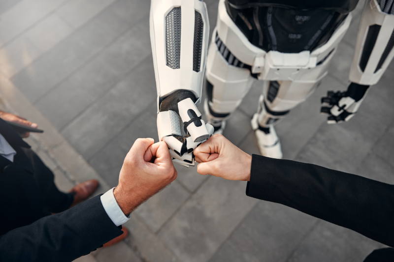 Profesionales caminando junto a un robot en la imagen del artículo de Directivos y Gerentes